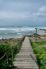 Obraz premium Beach landscape with wooden path with steps, waves, clouds