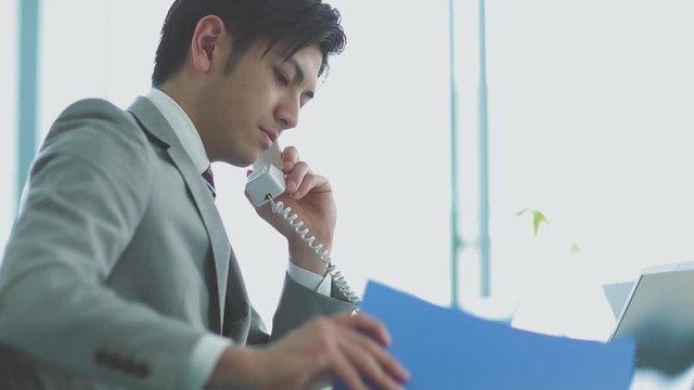Businessman talking on phone and working at desk in office