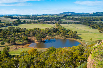 Fototapeta premium Small pond and native trees among meadows and pastures near Hanging Rock, Victoria, Australia