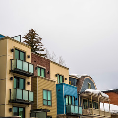 Square frame Residential buildings exterior with snowy roofs against cloudy sky in winter