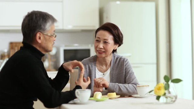 Senior couple sitting and talking at table at home