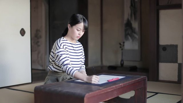 Woman practicing Japanese calligraphy in temple, Kyoto, Japan