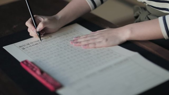 Woman practicing Japanese calligraphy in temple, Kyoto, Japan