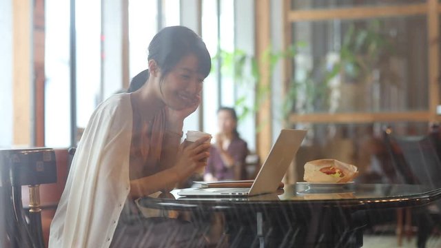 Businesswoman smiling while using laptop in cafe