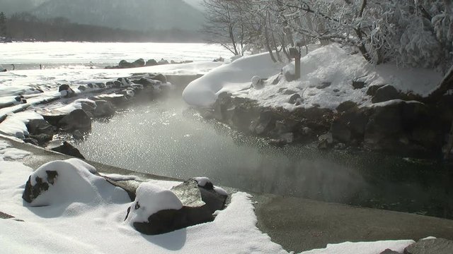 Hot spring of Lake Kussharo in winter with swans in background