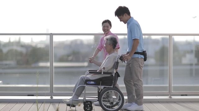healthcare professional and senior woman on wheelchair on walk, Japan
