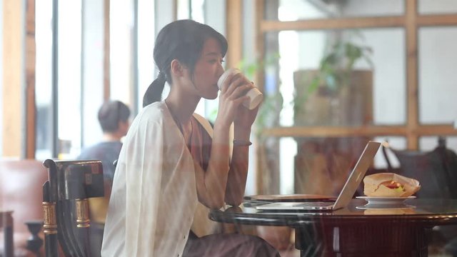 Panning shot of businesswoman drinking coffee at cafe