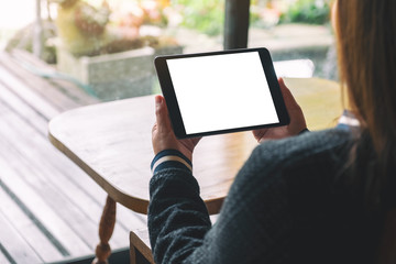 Mockup image of a woman sitting and holding black tablet with blank white desktop screen