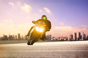 man riding sport motorcycle lean on curve road against urban skyline background
