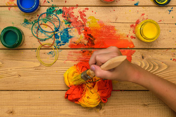 The girl does the job of painting t-shirts in the style of tie dye.