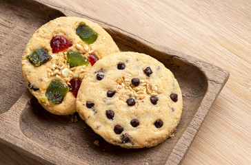 Chocolate chip cookie and mixed fruits cookie with wooden tray on the wood table. Delicious homemade baked cookie.