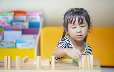happiness little girl learning construction with wooden blocks or wood blocks stack game. concept education.