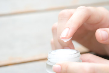 Hand of woman holding moisturizer cream and serum. She applying a facial cream , essential , oil , lotion and body cream for skin care, close up view and blur background. Beauty and Healthy Concept.