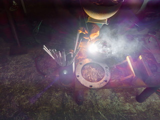 Close up worker welding steel with smoke and colourful of lights in industrial work shop.