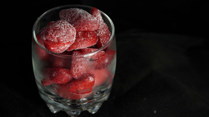 Frosty strawberries in glass on black background