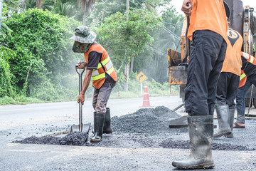 Group of workers working on repairing asphalt road. Workers on a road construction, industry and teamwork.