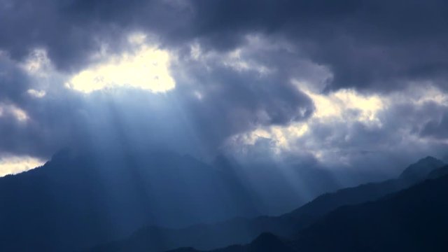 Timelapse&nbsp;of sunlight shining between flowing clouds over mountains