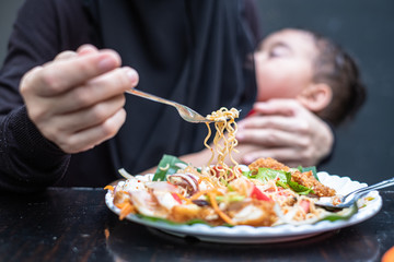 Mother eating spicy while baby sleep and breastfeeding in the restuarant. Baby in mother's hugging and breastfeeding while mother is eating.