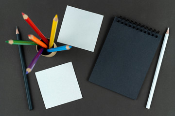 notes, black notebook and pencils lie on black table, and multi colored lgbt pencils stand in the...