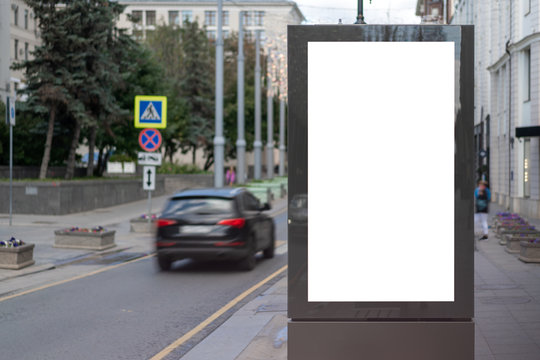 Mock Up Rectangular Vertical Lightbox On Street In City. Advertising Construction. Copy Space. Billboard On Sidewalk Narrow Street. Against Backdrop Building And Roadway.