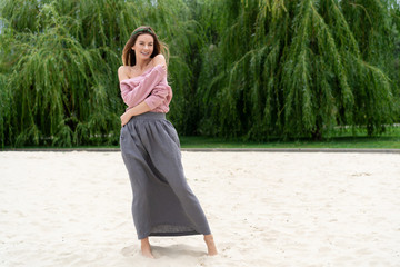 young European girl, natural appearance, long hair, beautiful face, gray long skirt, pink shirt,...