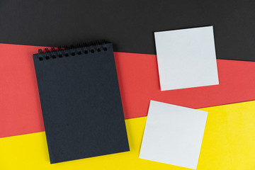 Blacklist Germany. Mourning, ban, sanctions, politics. black notebook and and two white notes lies on German flag. Mock up, copy space, pattern, cardboard texture.