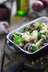 Baked, fried or grilled vegetables in ceramic form on a wooden mtole. Brussels sprouts, onions, garlic, olive oil