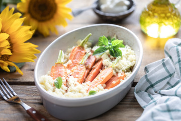 Young carrots baked with Pravanese herbs. couscous Sour cream, yogurt or fresh cream. Flowers sunflower wooden table
