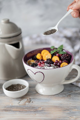 Homemade granola with nuts, chia seeds and fruit in a breakfast mug. Light photo.