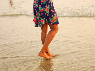 woman standing bare feet on sea water during golden hours in summer