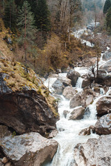 Small cliffy mountain spring waterfall in Abkhazia. Craggy ridge cliff with water bursts. Cold water rocky mountains of waterfall. Rock mountains falling stream.