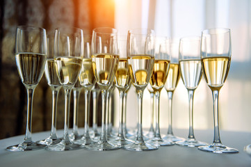 A row of glasses filled with cold champagne lined up, ready to be served. Glasses with Martini on the table - party background. Welcome drink on the wedding ceremony.