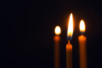 Burning candles on dark background, space for text. Symbol of sorrow