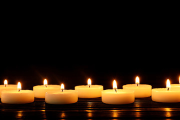 Burning candles on table against black background, space for text
