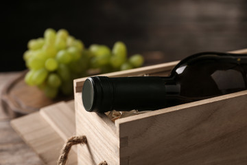 Open wooden crate with bottle of wine on blurred background