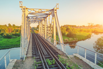 Railway bridge over a small river, sunset view.