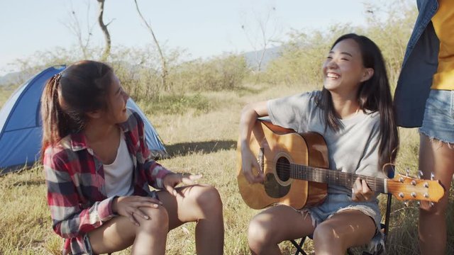 Asian teen group women singing, Sitting play a guitar at campsite in the summer time. Vacation  relaxation trip concept 