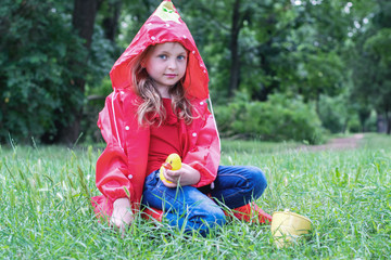 Happy child girl laughs and plays under summer rain