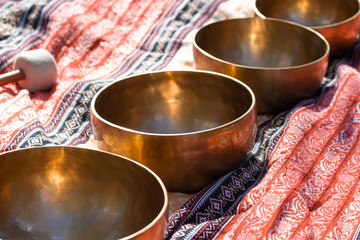 Indian Tibetan bronze healing bowls lie on a sari in perspective. Singing healing bowls of Tibetan...
