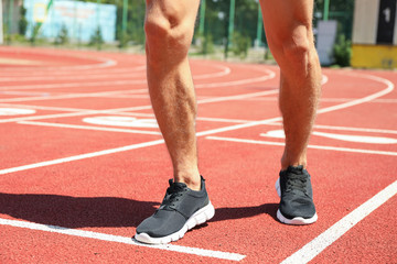 Man in sneakers on red athletic running track, close up