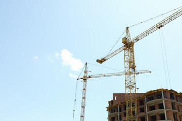 Big yellow crane in construction site against blue sky