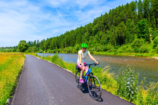 Young woman riding bike on cycling way along Dunajec river near Nowy Targ, Tatra Mountains, Poland
