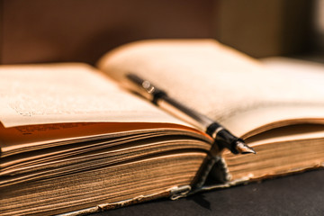 Fountain pen on open antique book. Educational concept.