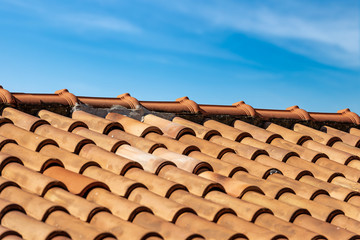 Closeup of a house roof with a terracotta tiles (clay), on blue sky with clouds. Italy, Europe
