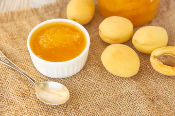 Home made organic apricot jam in glass jar and ripe apricots on wooden rustic table