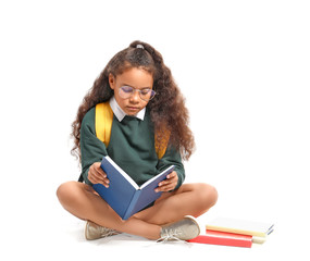African-American schoolgirl reading book on white background