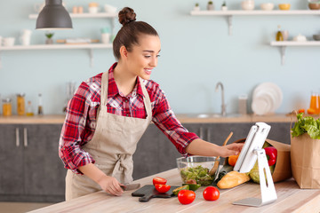 Beautiful woman preparing tasty vegetable salad in kitchen at home