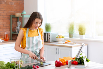 Beautiful woman preparing tasty vegetable salad in kitchen at home