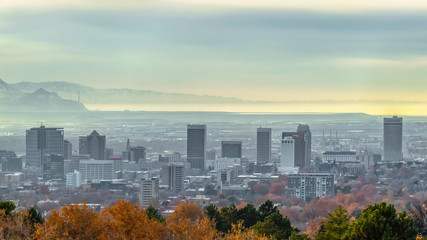 Obraz premium Panorama frame Panorama of populous city with buildings and snowy mountain under cloudy sky