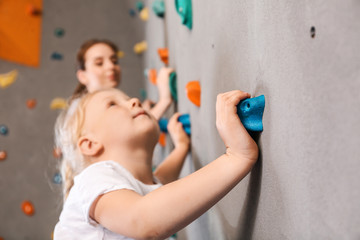 Little girl climbing wall in gym